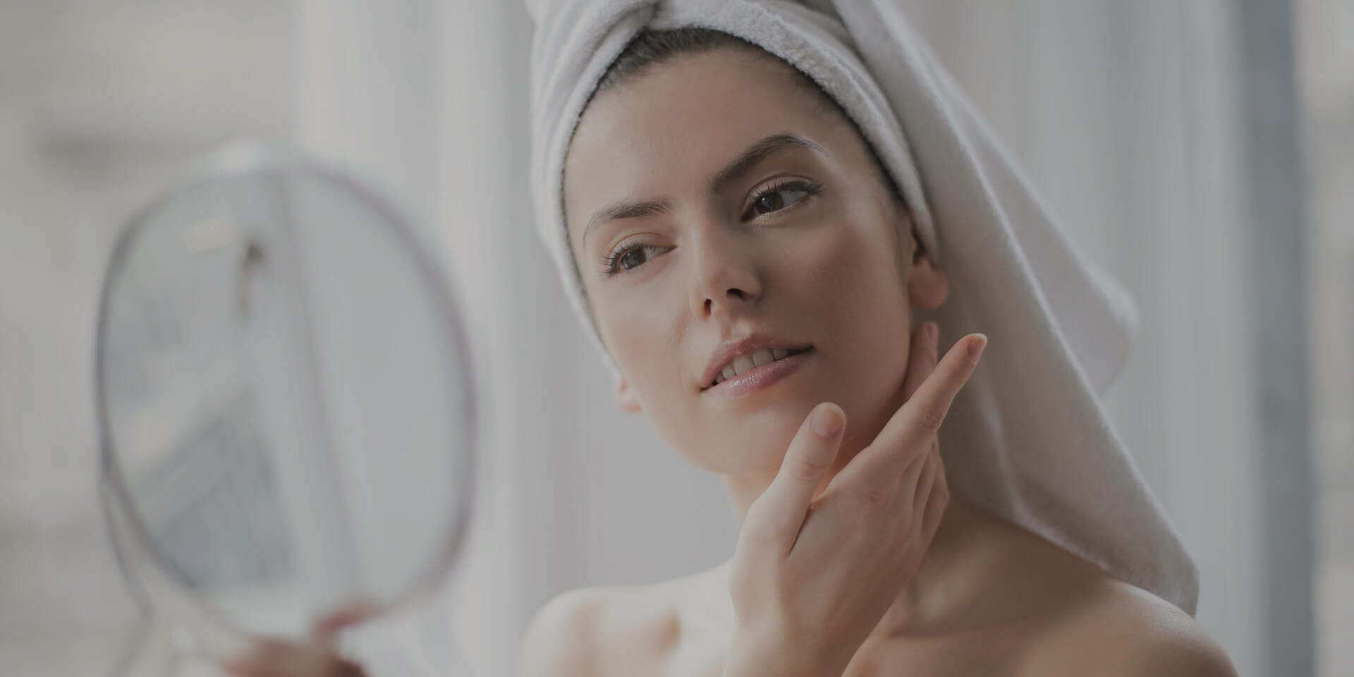 Woman applying skincare in a bright bathroom